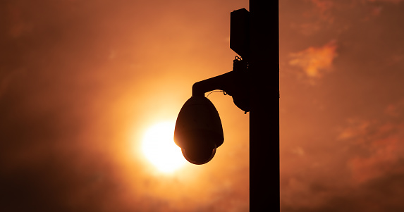 Surveillance camera on a pillar against the backdrop of the setting sun