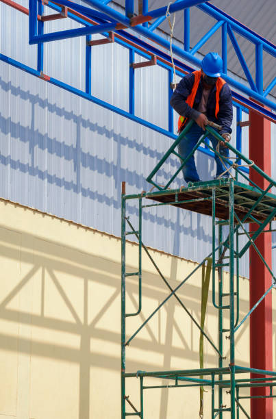 istock Construction worker installing scaffolding for working on top of roof warehouse building structure in construction site 1353729536