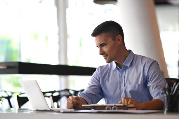 istock Confident businessman sitting in modern office and checking email on laptop computer. 1353729784