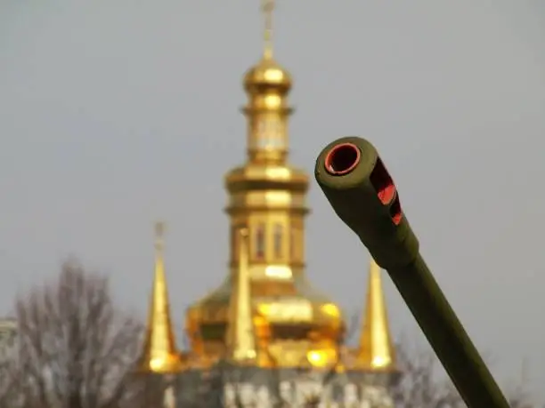 Barrel of a Soviet-era artillery gun and an Orthodox Church golden dome.  This image was taken during Spring near the Motherland Monument in Kyiv, Ukraine