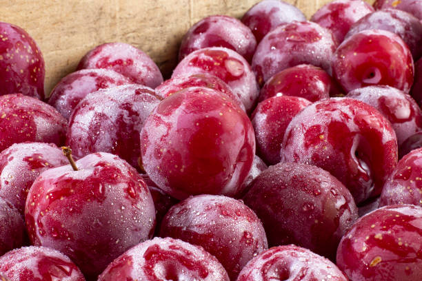 istock Ripe large plums in a wooden box close-up 1353734184