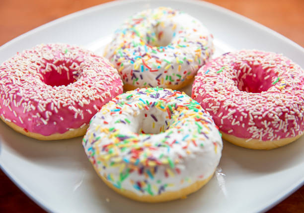 American style donuts with pink glazing and colorful star shaped sprinkles.