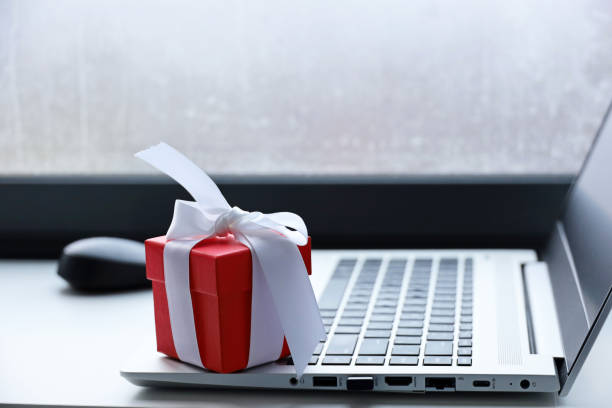 istock Red gift box on laptop keyboard near the window 1353741295
