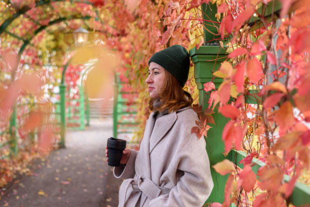 istock Woman drinking from reusable cup at autumn park 1353742634
