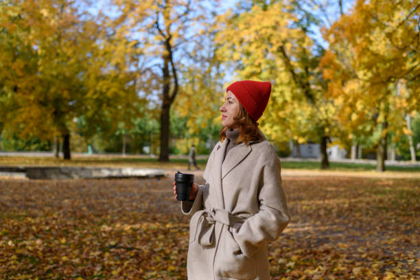 istock Woman drinking from reusable cup at autumn park 1353742785