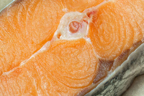 Proper healthy nutrition. Raw red salmon fish slice close-up with texture. Product containing vitamin D, A, B, C, PP phosphorus, iodine, calcium, potassium, sodium, magnesium, zinc, fluorine, omega-3
