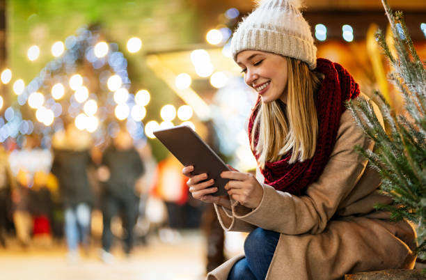 shopping christmas travel people concept. happy woman with shopping bag using digital device outdoor - ipad shopping gift retail imagens e fotografias de stock