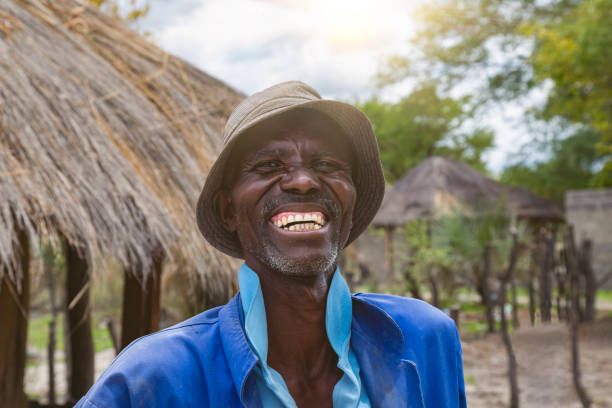 Happy elderly African man portrait, in front of his house in an African village