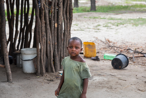 African child walking in front of the outdoors kitchen in the village