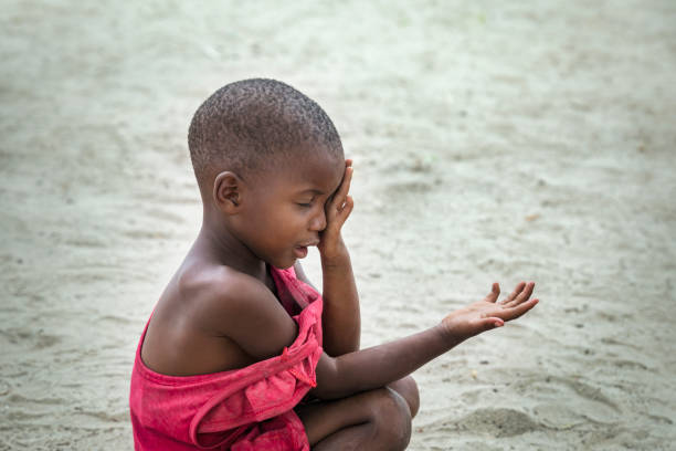 Poor African child with a red t-shirt and a sad face stock photo