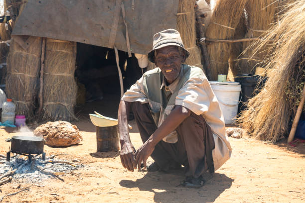 old man in an African village with shacks with thatched roof