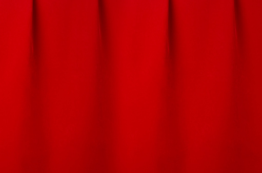 Saturated scarlet red silk curtain with smooth creases as luxury classic theatre abstract background.