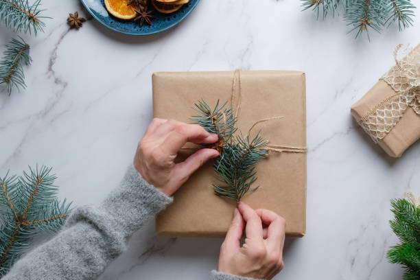 istock Young woman decorates Christmas gift box. Overhead view 1353758827