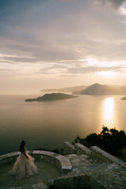 istock The bride stands on the observation deck overlooking the island at the sunset, back view 1353758897