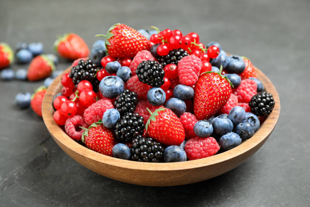 istock Mix of different fresh berries in bowl on grey table 1353761238