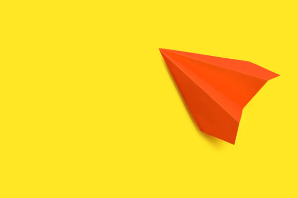 istock Orange paper plane on yellow background, top view. Space for text 1353764048