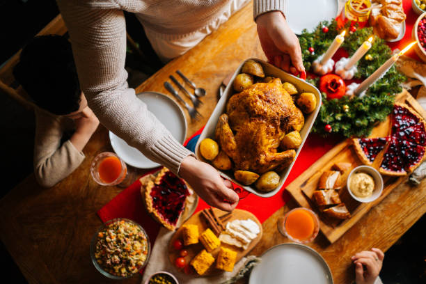 nahaufnahme des jungen vaters männlich, der ein gericht mit gebackenem heißem truthahn auf den weihnachtstisch stellt, serviert für die weihnachtsfeier der familie - christmas food dinner turkey stock-fotos und bilder