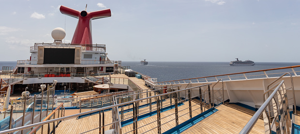 Saint Vincent and the Grenadines - May 8, 2020: Panoramic shot of open decks and red funnel on Carnival Freedom. Carnival Valor, Carnival Fascination, blue sky with white clouds in the background.