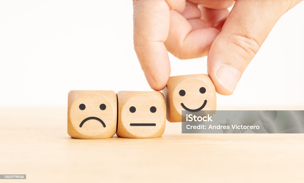 Customer service evaluation concept Customer service evaluation concept. Hand picking the happy face emoticon on wooden block Consumer Confidence Stock Photo