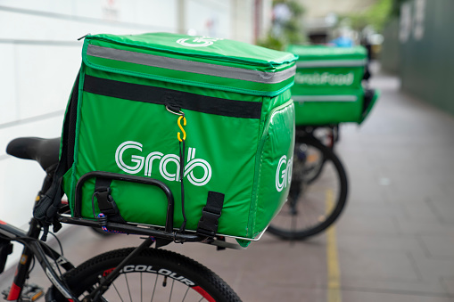 Singapore, Singapore - November 8, 2021: Food delivery bags branded with the Grab logo, mounted on bicycles parked outside the Jurong Point shopping mall.