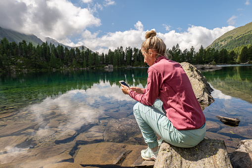 Woman text messaging on mobile phone in nature, connection in remote location