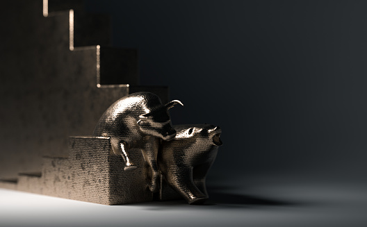 Bull and bear statuettes made of copper representing upward and downward trending economic graphs side by side on a dimly lit background - 3D render