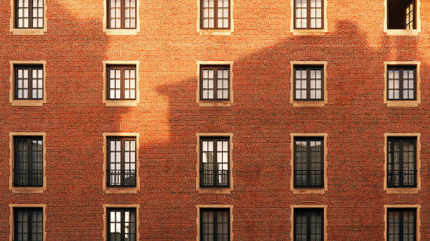 Old red brick wall with windows and shadow of another building at sunset Old brick wall with windows and shadow of another building at sunset. Urban European scene. houses in brussels stock pictures, royalty-free photos & images