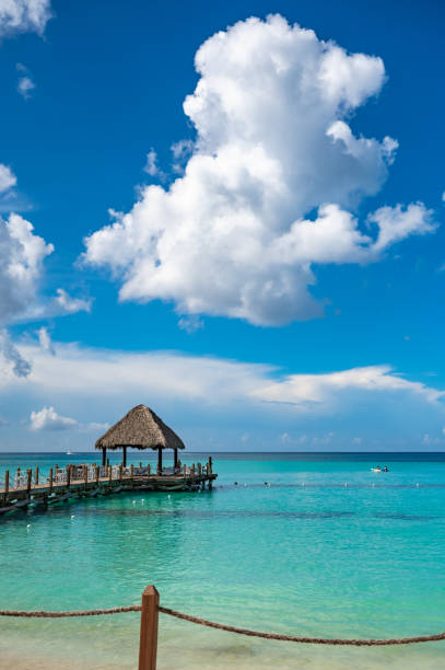wooden gazebo with a roof of palm leaves on a pier in the caribbean sea