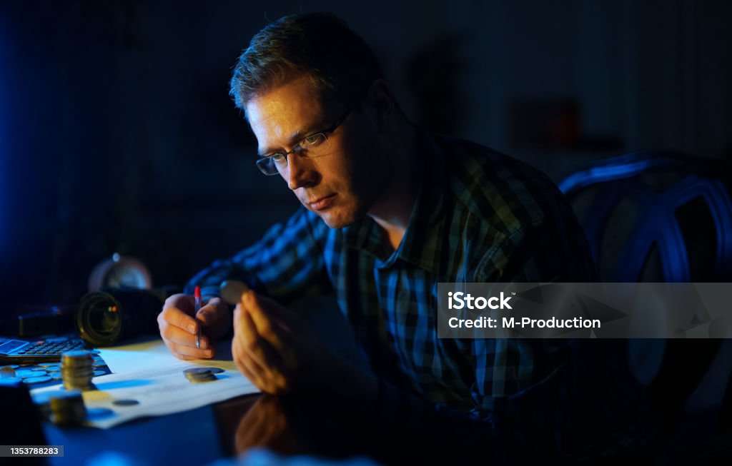 Male numismatist examines collection of coins. Numismatics Stock Photo