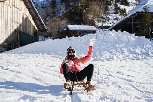 Happy girl speeding with vintage sledding on snow high mountain - Focus on shoes
