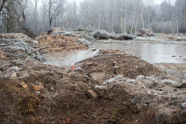 istock Construction site with sand piles, bricks, frosted trees and frozen puddles on a cold autumn morning 1353789057
