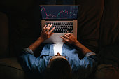 Trader analyst looking at laptop monitor at night