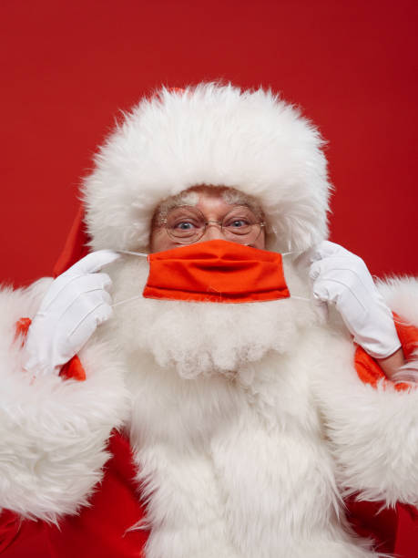 istock Santa covers his face with a red protective face mask, we see him in close up on a red background in a professional illumination 1353790936