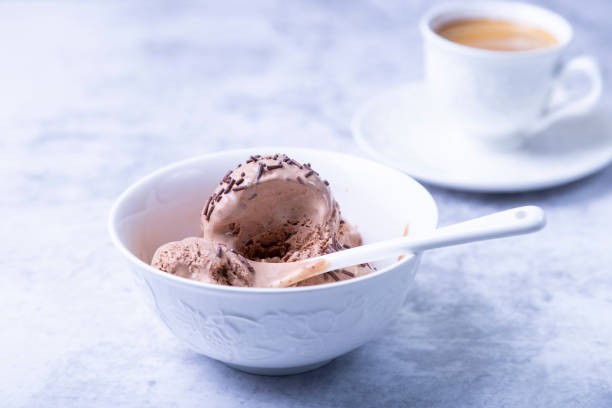 istock Chocolate ice cream with chocolate topping in a white bowl on a white background. Three scoops of homemade ice cream, a cup of coffee. Close-up 1353794386