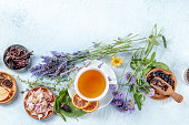A cup of tea with dry fruit, flowers, and herbs, shot from the top