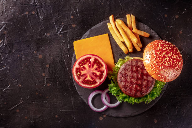 burger ingredients, shot from above on black with copy space - sesame bun american culture cheddar imagens e fotografias de stock