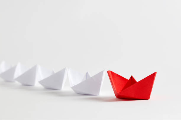 istock Red paper boat leads white paper ships. Teamwork, cooperation, leadership, partnership and participation 1353794784