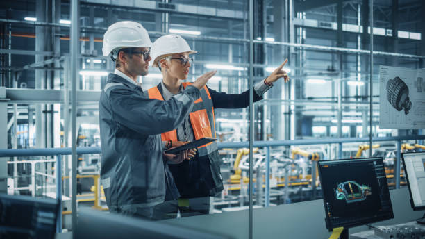 istock Male Engineer and Female Industrial Product Designer Discuss Work while Using Tablet in Office at a Car Assembly Plant. Industrial Specialists Working on Vehicle Design in Technological Factory. 1353796803