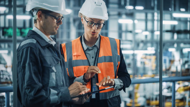 istock Male Engineer and Female Industrial Product Designer Discuss Work while Using Tablet in Office at a Car Assembly Plant. Industrial Specialists Working on Vehicle Design in Technological Factory. 1353796817
