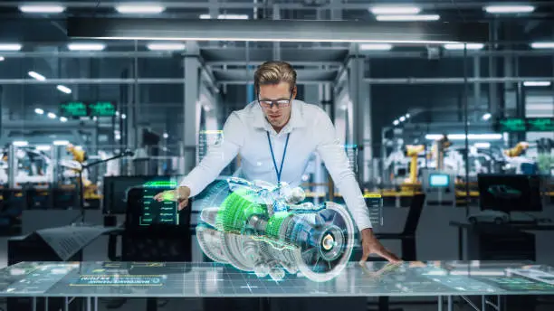 Photo of Confident Engineer in White Shirt Working on Jet Engine with Use of Augmented Reality Hologram in an Office at Plane Assembly Plant. Industrial Specialist Working in Technological Development Facility