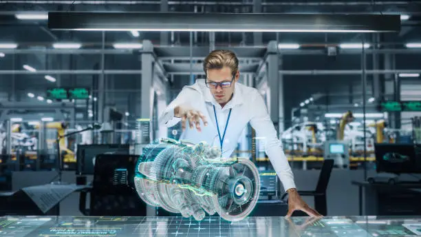 Photo of Confident Engineer in White Shirt Working on Jet Engine with Use of Augmented Reality Hologram in an Office at Plane Assembly Plant. Industrial Specialist Working in Technological Development Facility