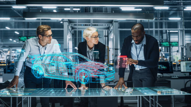 diverse team of engineers working in office at industrial factory. industrial designers discuss electric car augmented reality hologramm. specialists work in technological car development facility. - electric motor fotos imagens e fotografias de stock