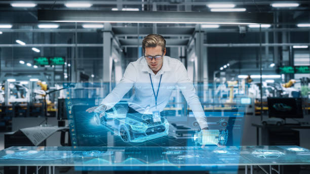 istock Confident Engineer Working on a New Electric Car with Use of Augmented Reality Hologram in an Office at Car Assembly Plant. Industrial Specialist Working in Technological Vehicle Development Facility. 1353796862
