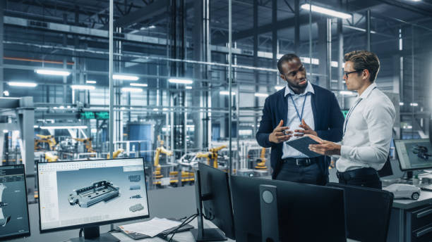 istock Two Diverse Automotive Industrial Engineers Talking About Vehicle Production while Standing in Office at a Car Assembly Plant. Industrial Specialists Discuss Work Projects on Tablet Computer. 1353796935