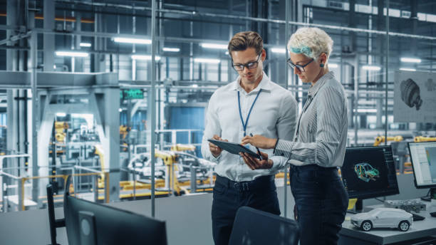 istock Male Engineer and Female Industrial Product Designer Discuss Work while Standing in Office at a Car Assembly Plant. Industrial Specialists Working on Vehicle Design in Technological Factory. 1353796985