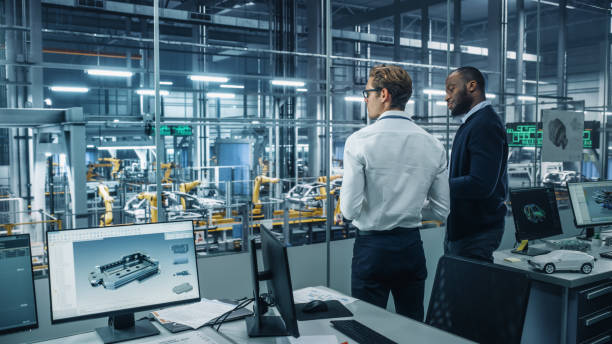 istock Two Diverse Automotive Industrial Engineers Talking About Vehicle Production while Standing in Office at a Car Assembly Plant. Industrial Specialists Discuss Work Projects on Tablet Computer. 1353797015