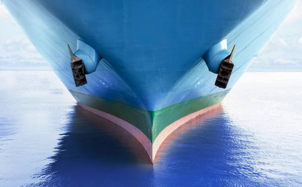 Front view of large blue merchant cargo ship in the middle of the ocean. Performing cargo export and import operations. Front view of large blue merchant cargo ship in the middle of the ocean. Performing cargo export and import operations with horizon line and beautiful sky. industrial ship stock pictures, royalty-free photos & images