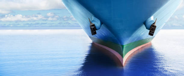 Front view of large blue merchant cargo ship in the middle of the ocean. Performing cargo export and import operations. Front view of large blue merchant cargo ship in the middle of the ocean. Performing cargo export and import operations with horizon line and beautiful sky. anchor vessel part stock pictures, royalty-free photos & images