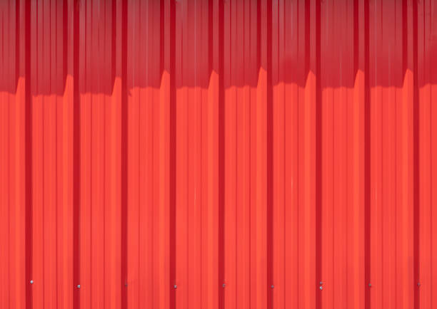 istock red metal corrugate wall with light and shadow. red metal sheet background and texture. 1353799409