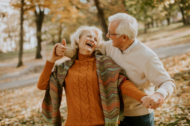 pareja de ancianos abrazados en el parque de otoño - senior adult mature adult senior couple heterosexual couple fotografías e imágenes de stock